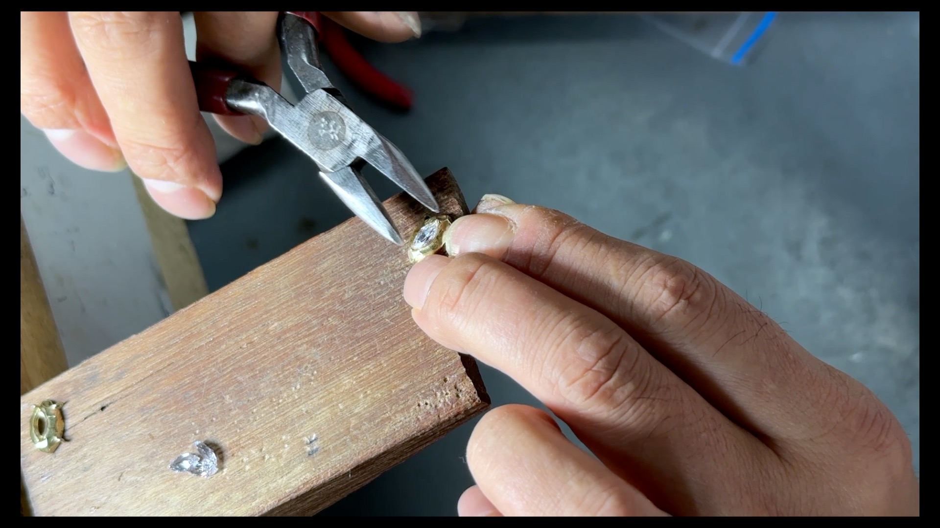 Jeweler hand-setting a gemstone in a ring, trimming and burnishing prongs for a secure fit.
