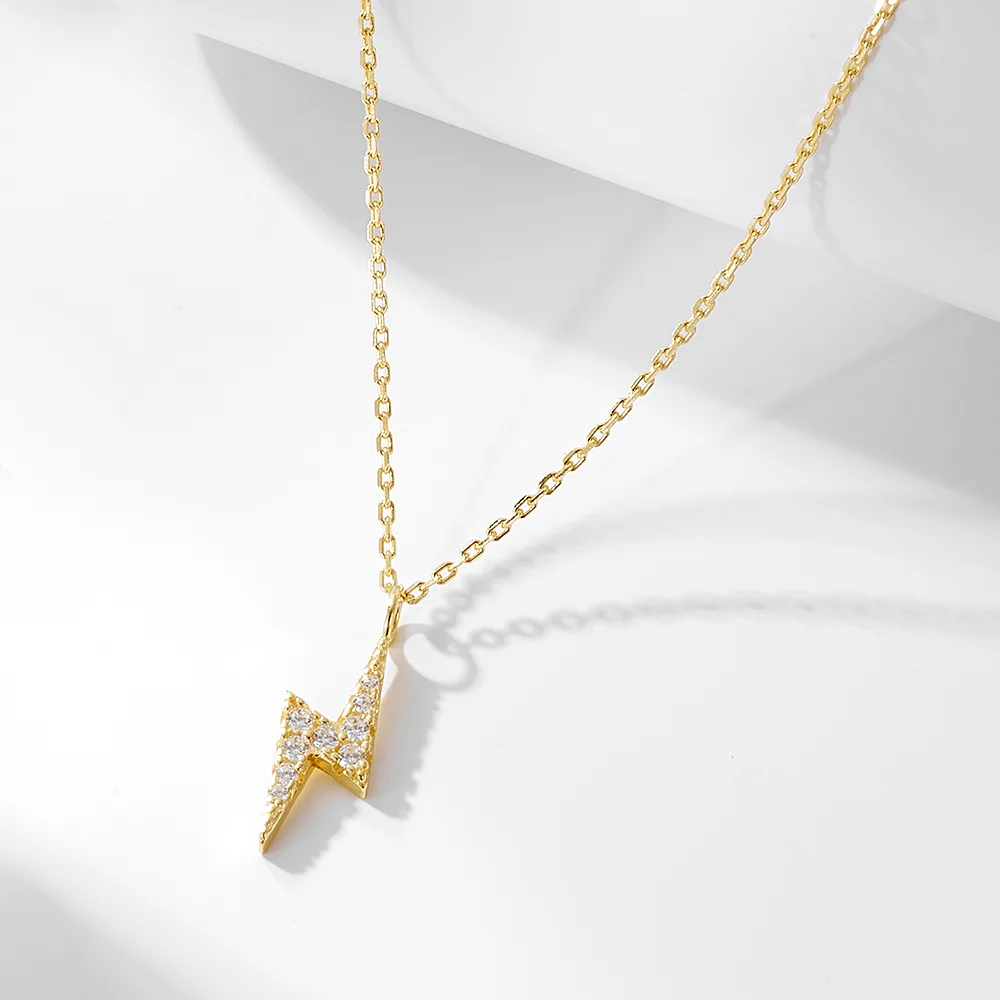 Lightning bolt pendant necklace in gold plating with pavé cubic zirconia, trendy jewelry symbolizing energy and confidence.
