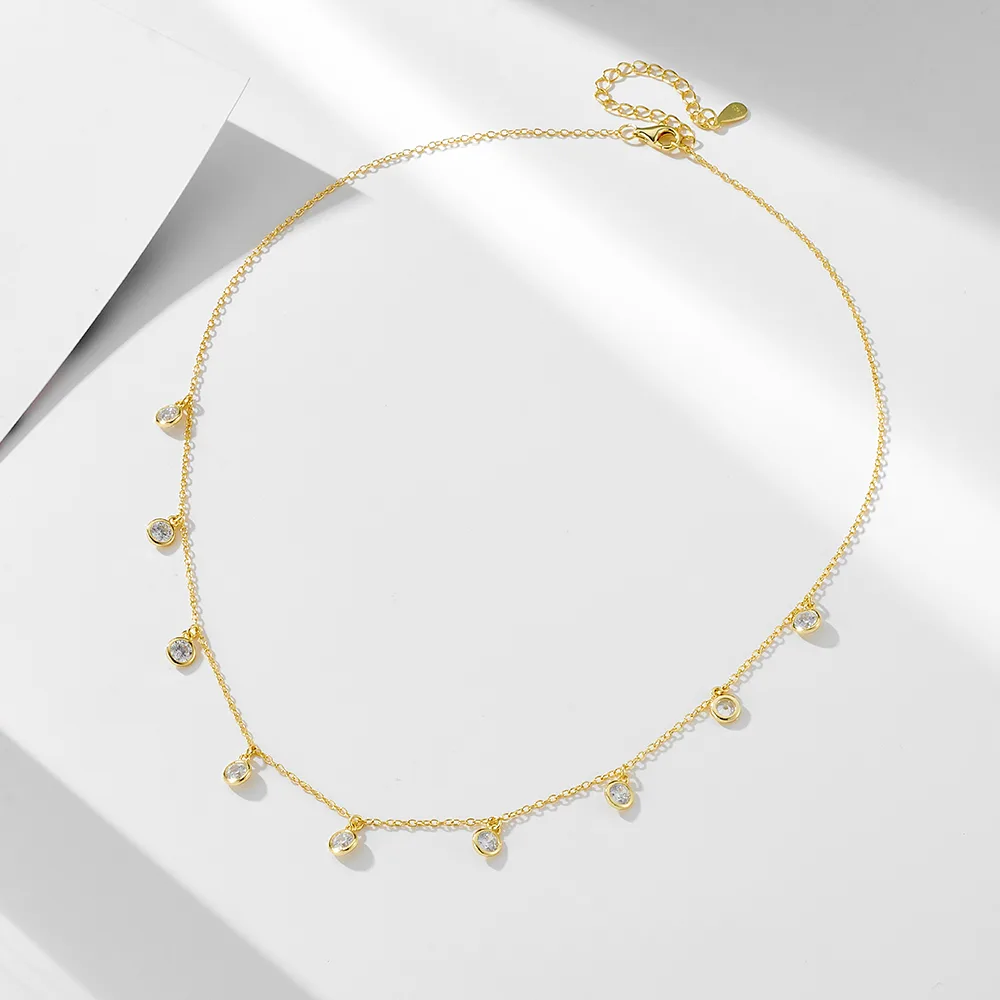 Dainty gold drop necklace with multiple bezel-set cubic zirconia charms, minimalist and elegant layering jewelry.