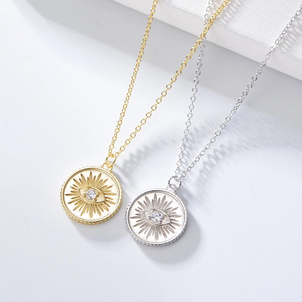 Sunburst medallion pendant necklaces in gold and silver plating, engraved design with cubic zirconia eye center.