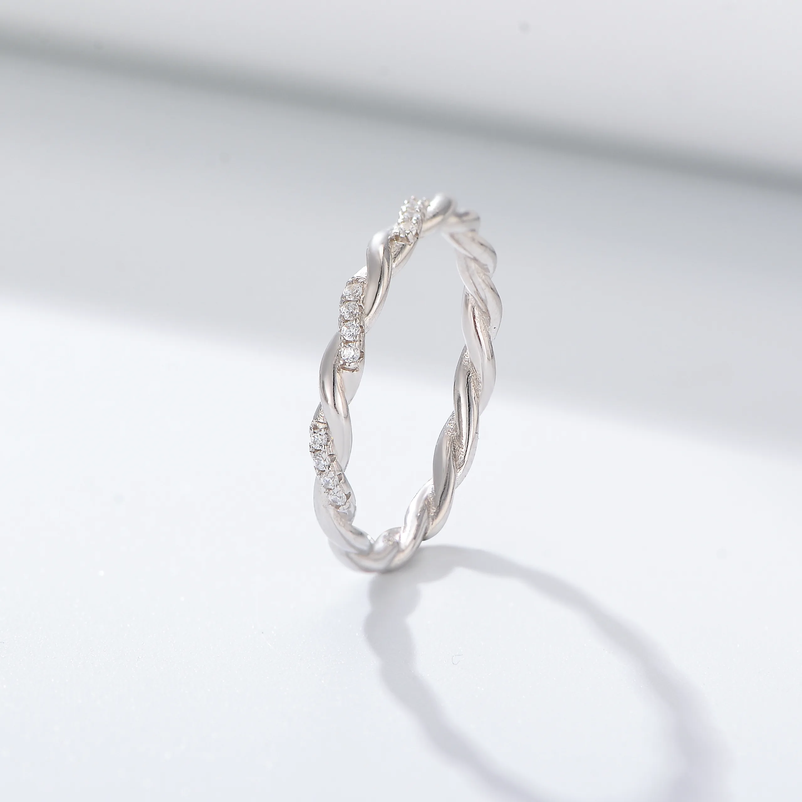 Sterling silver twisted band ring with pavé-set cubic zirconia, delicate braided design for modern style.
